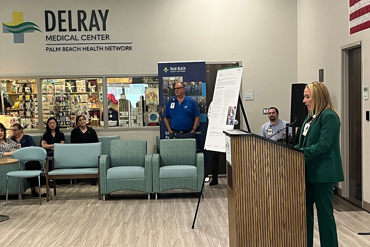 A woman at a podium speaking to a small crowd in a medical building